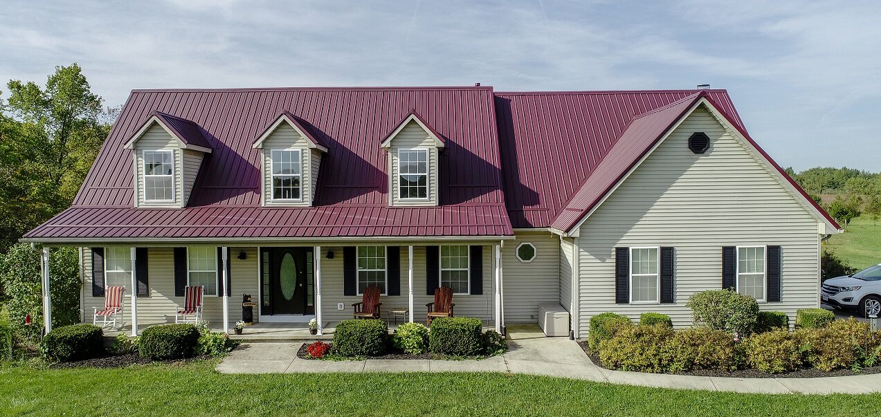 Burgundy metal roof with three dormers on a light-colored Central Ohio home