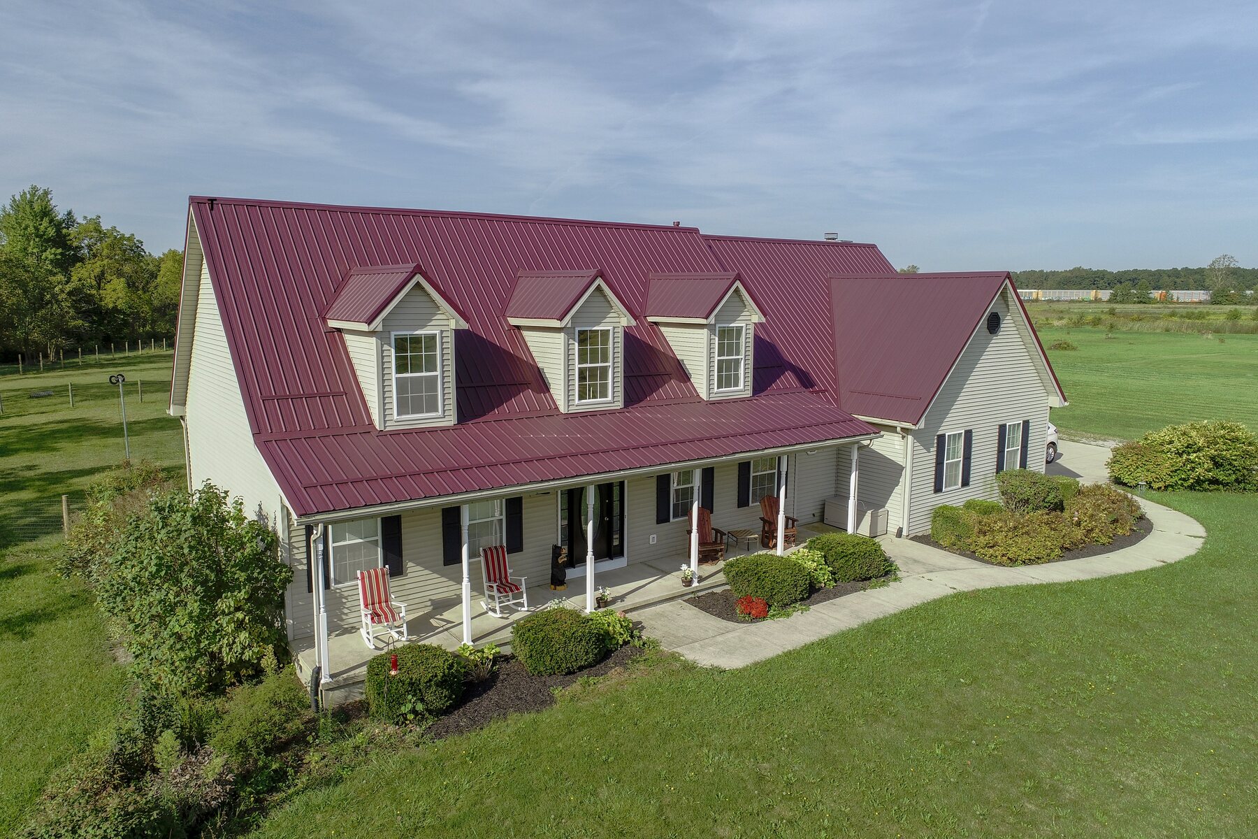 Burgundy metal roof on a white farmhouse with dormers in Central Ohio