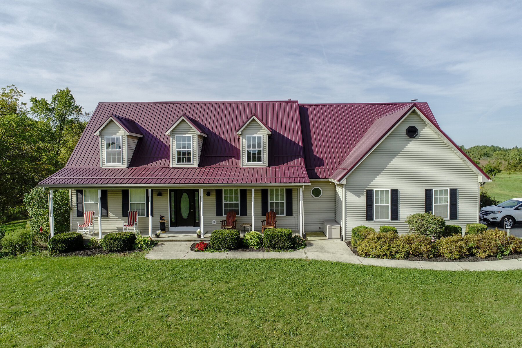 Burgundy standing-seam metal roof on a white home near Bear Swamp Road