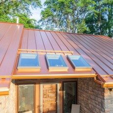 Close aerial view of a copper-colored standing-seam roof